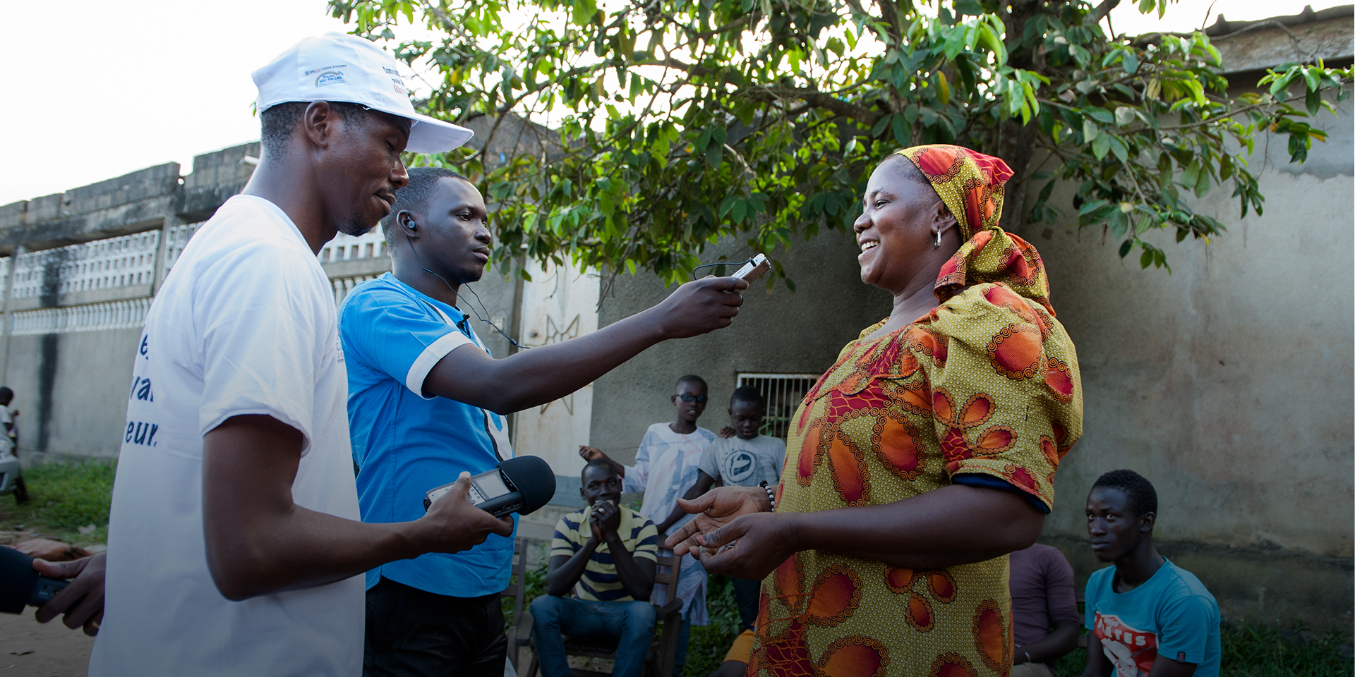 Image of two young men with recorders interviewing a smiling woman on the street.