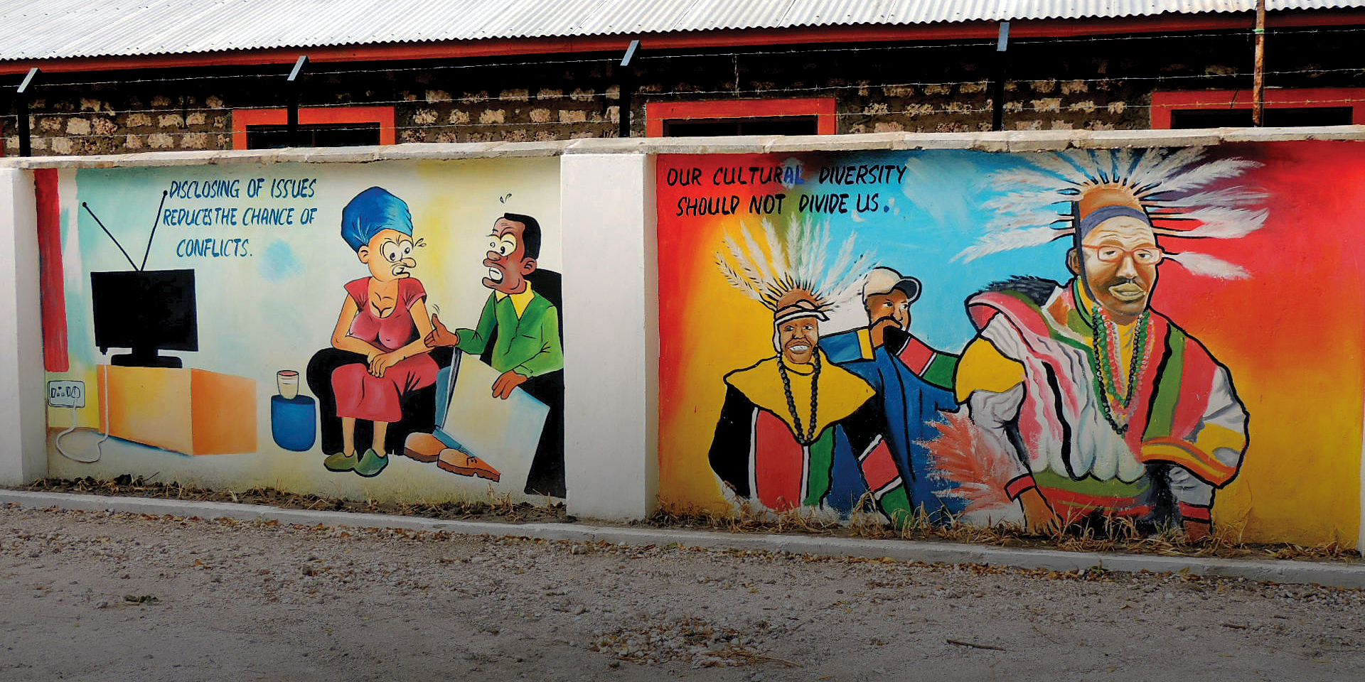 Image of two brightly colored murals side by side on a dividing wall. One addresses conflict resolution while the other celebrates cultural diversity.