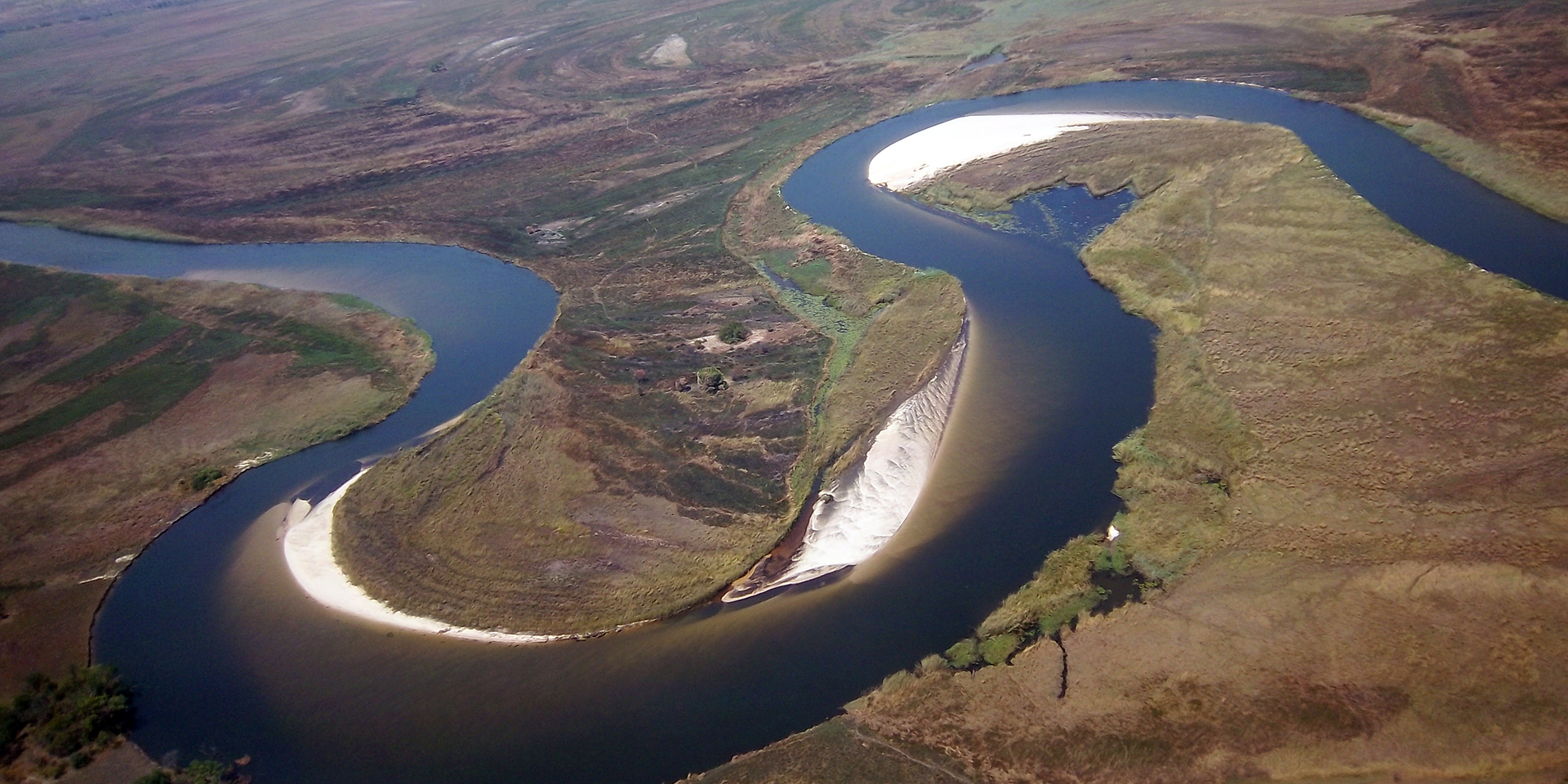 An aerial view of a large river snaking through a green landscape.