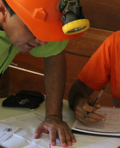 A pair of miners looking over documents on a table.