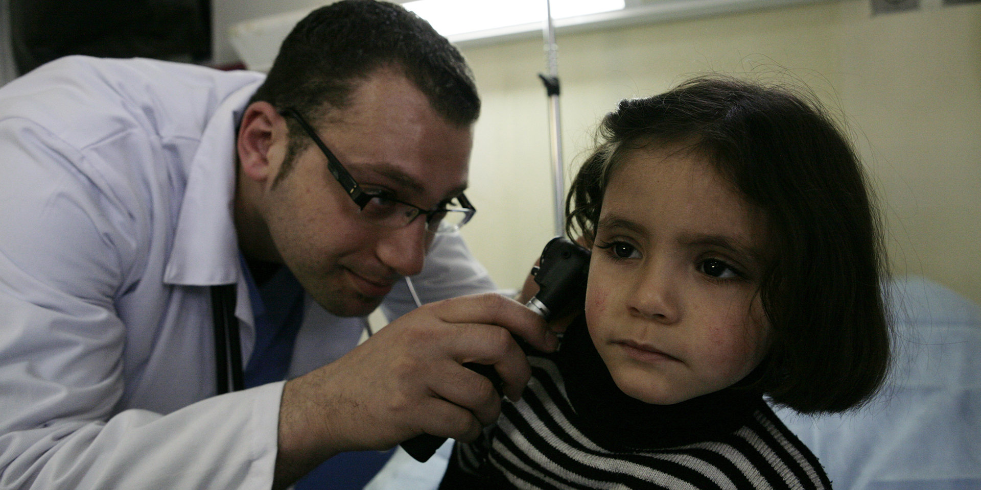 Image of a doctor checking a young girl's ear with an otoscope.