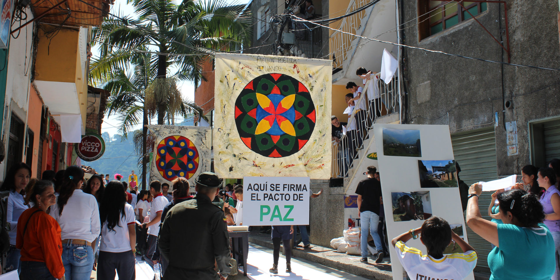 A street fair with several colorful banners decorating the road. The closest banner reads 