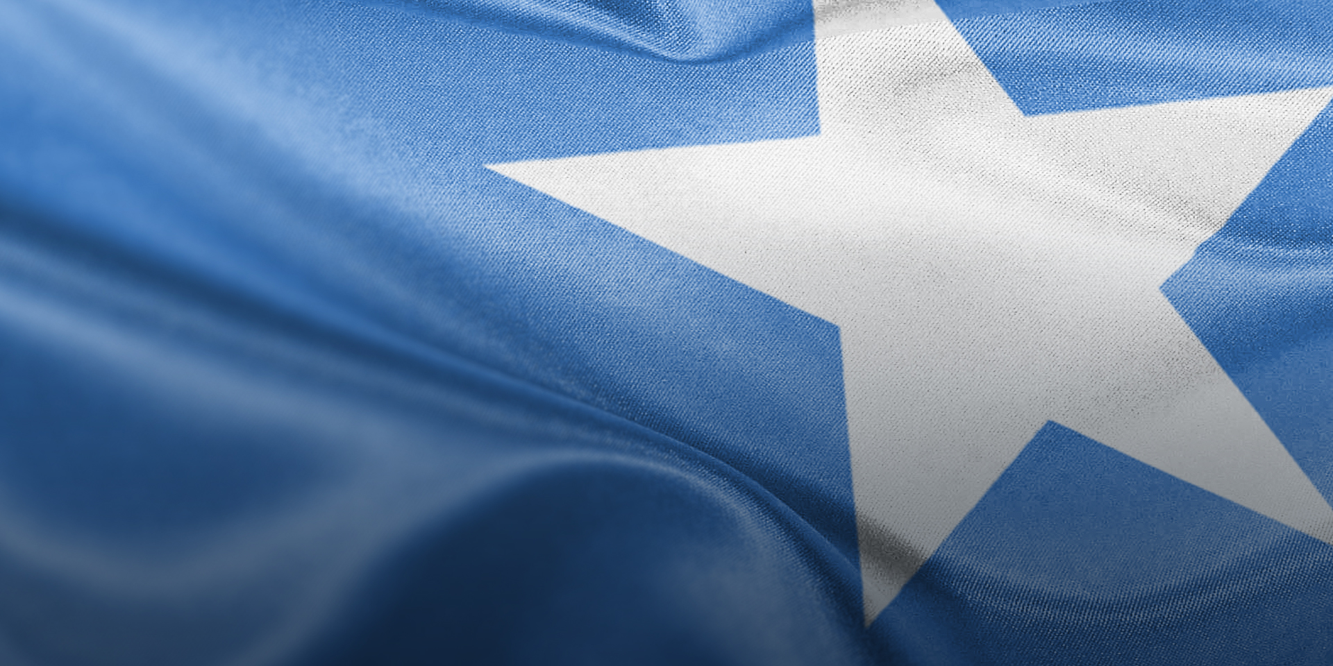A close-up image of the flag of Somalia: a light blue background with a large white star in the center.
