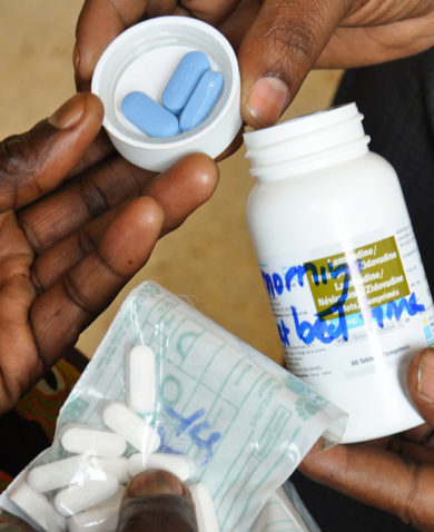 Image of a person giving medication to people in the form of pills.