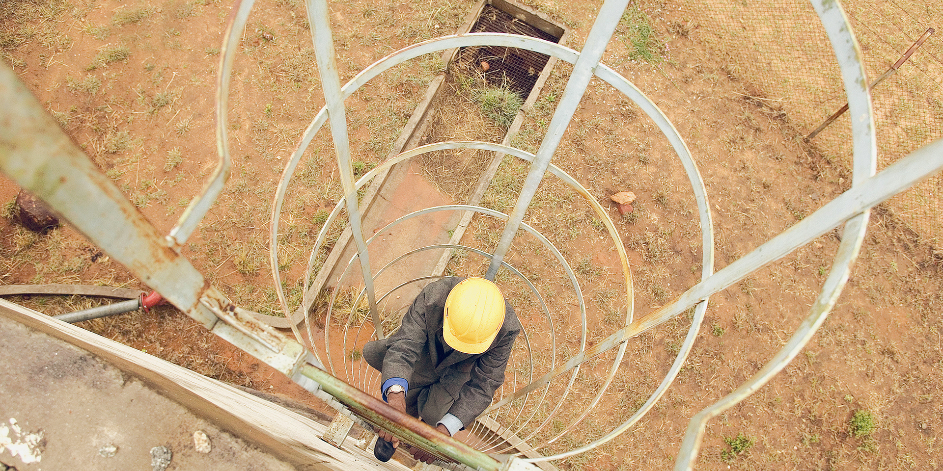 A man in a suit climbing the ladder of a water reservoir.