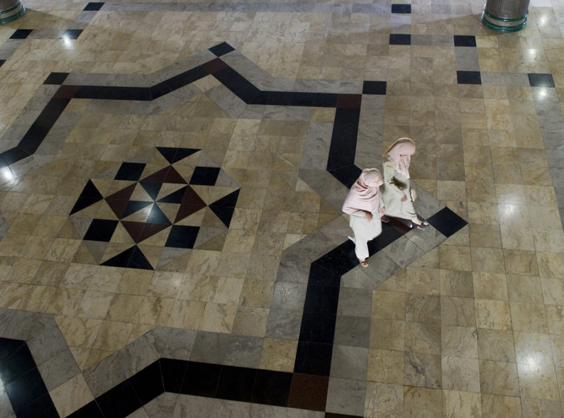 Overhead view of an intricately tiled floor with two women walking.