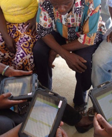 Several people sitting together in a circle as three of them work on tablets.