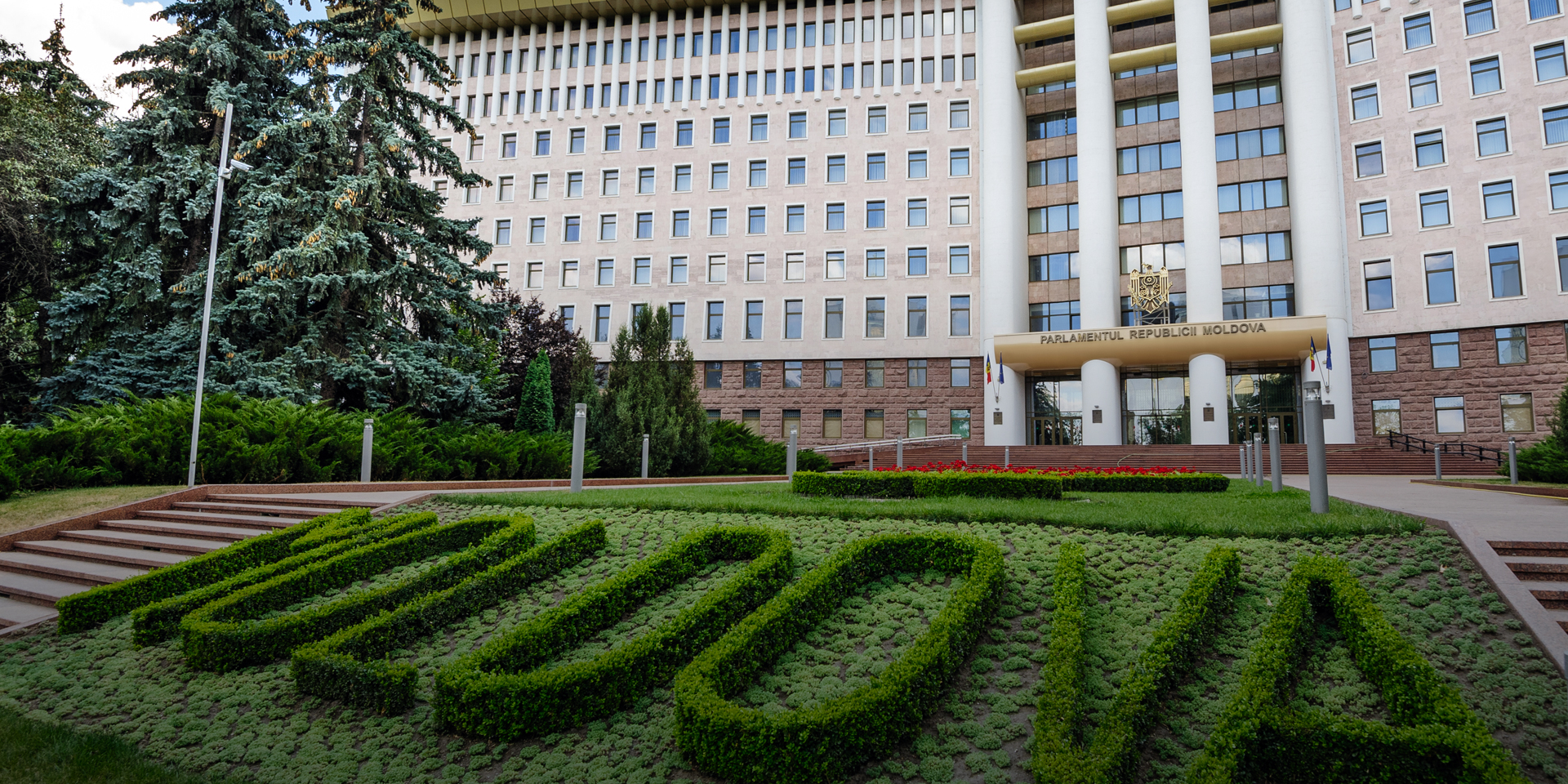 The front of Moldovan parliament with green hedging cut into the word 