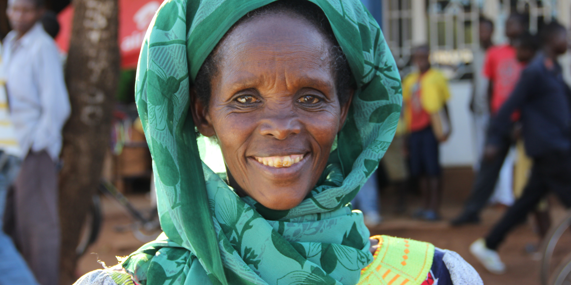 Image of a smiling woman standing on a busy street.