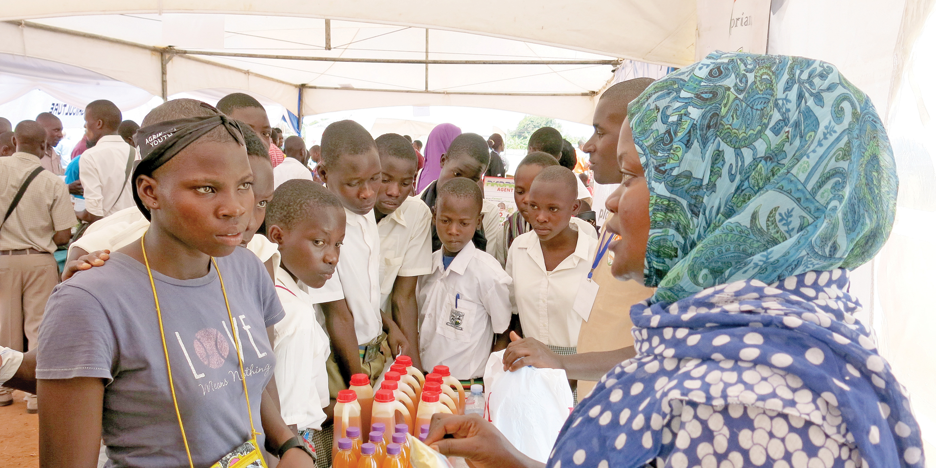 A woman at a juice stand speaking to youth.