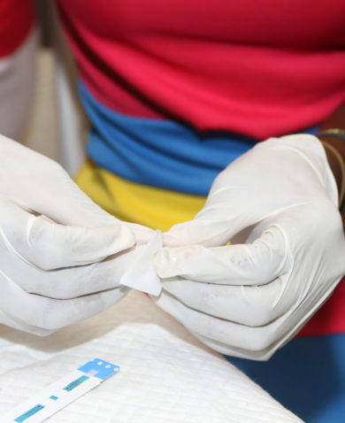 A close-up image of hands with latex gloves preparing a lab test.