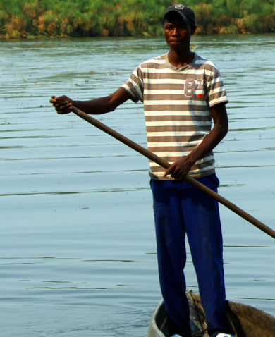 A man rowing a small boat in a lake.