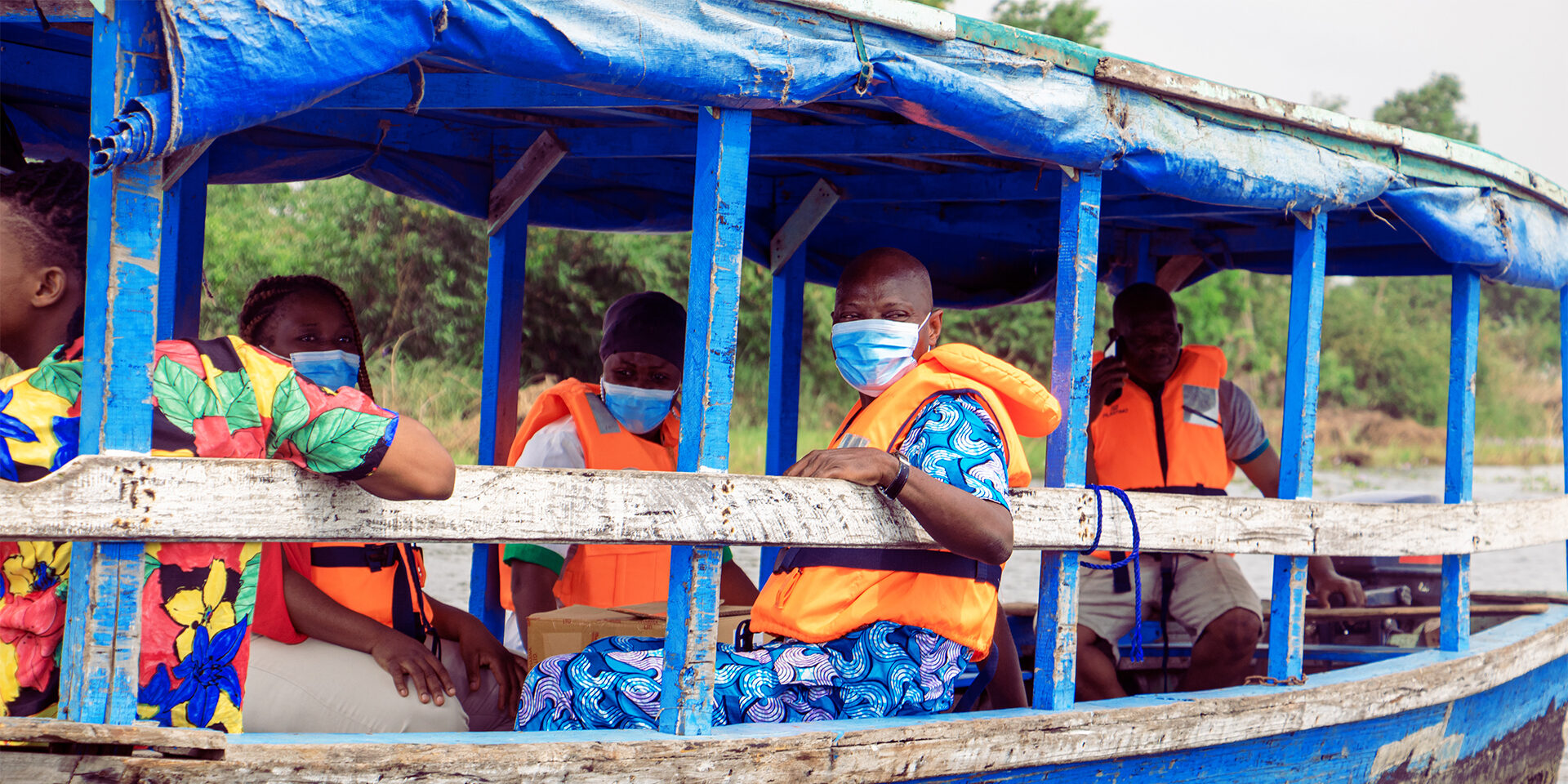 Several people riding in a blue wooden boat.