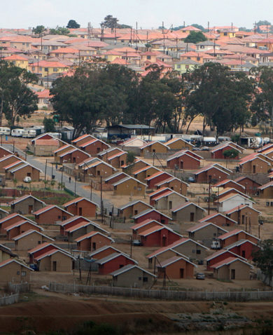 An aerial view of a large neighborhood with tan, red, and grey houses peppered throughout.