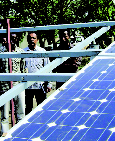 Image of several men standing beside a large solar panel.