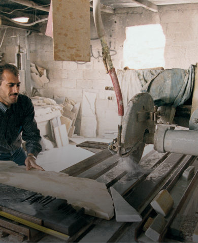 A man cutting stone slabs using a large table saw.