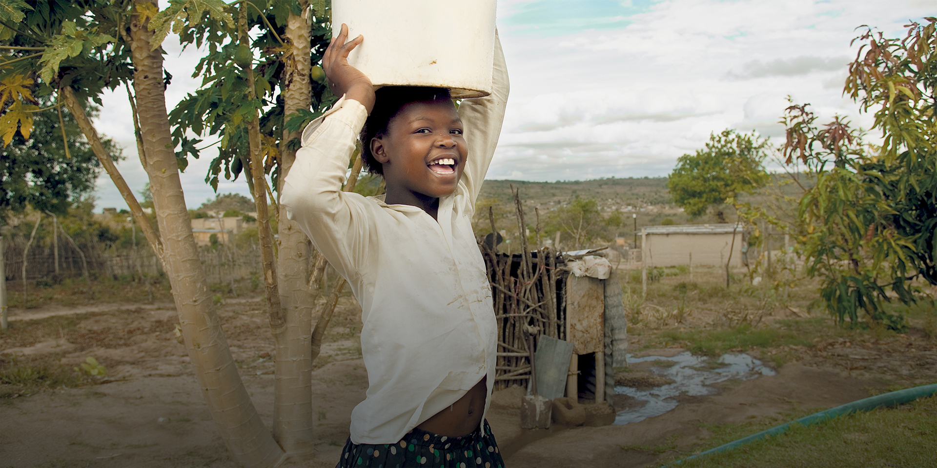 Smiling girl in South Africa carrying water