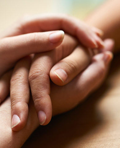 A close-up of two people holding hands in comfort.