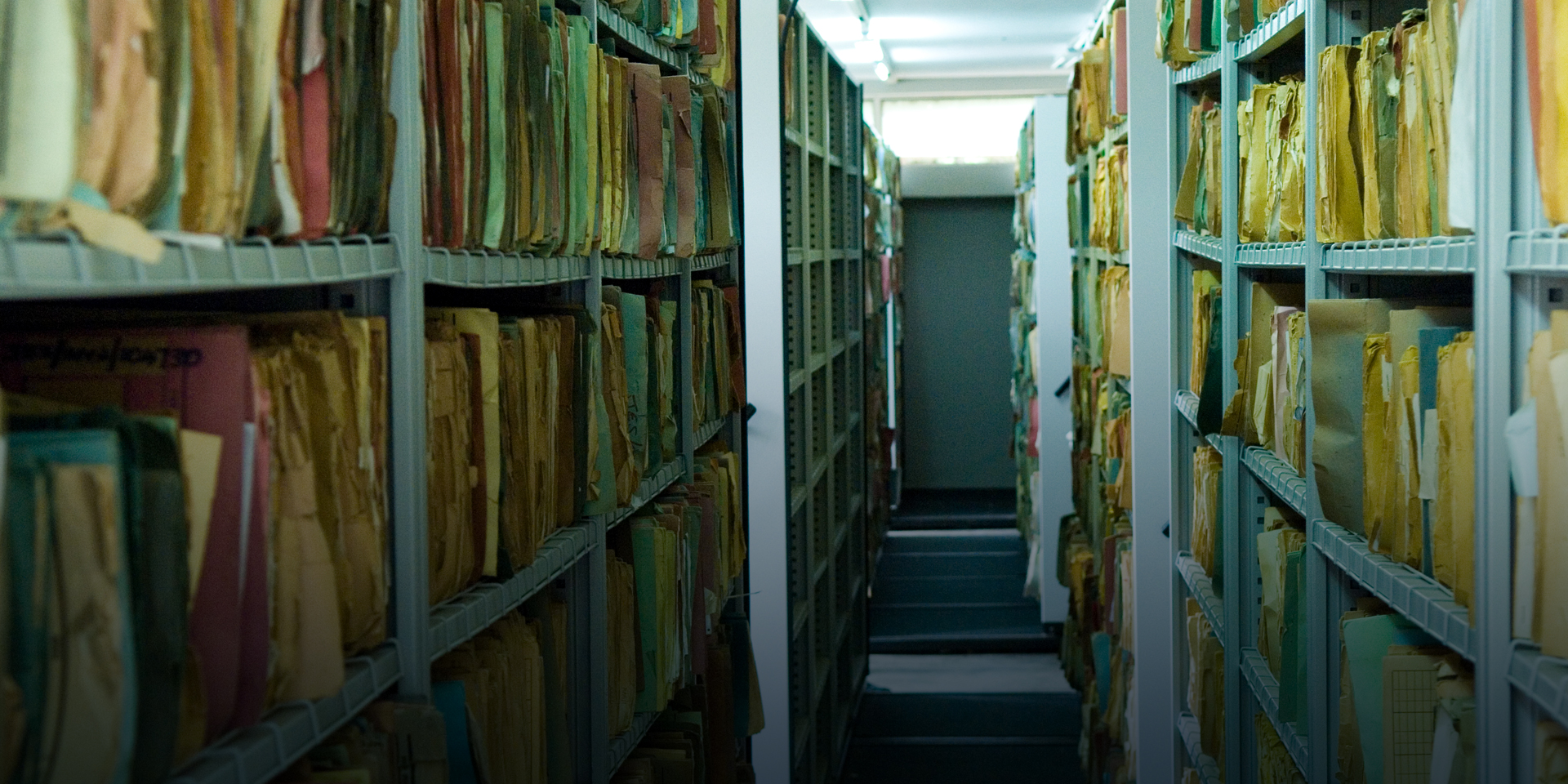 An aisle in a file room with several manilla envelopes filling shelves on each side.