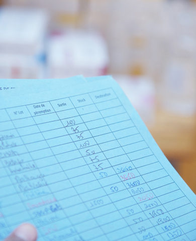 A close-up image of a person holding pages of a ledger.