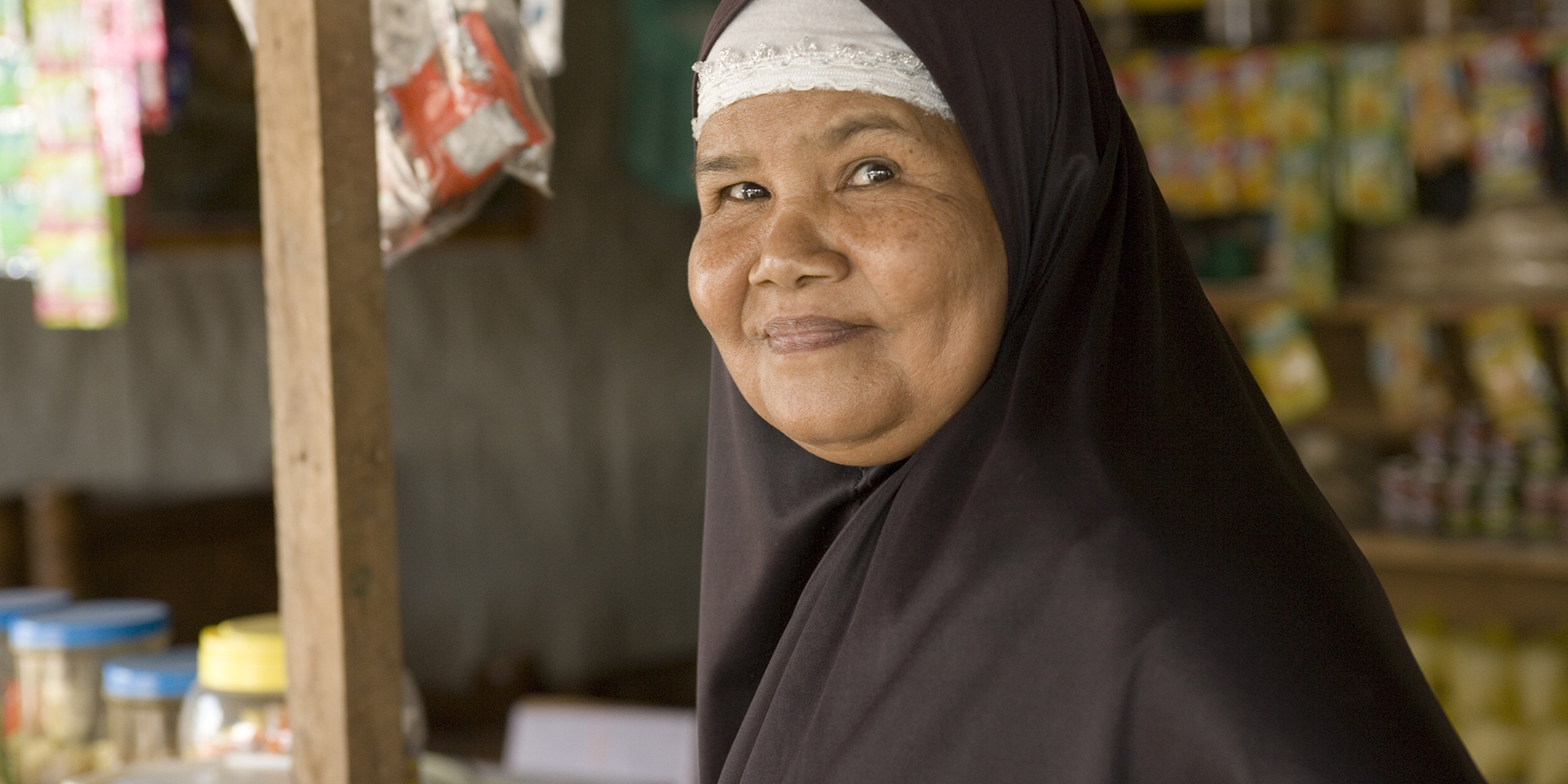 Image of a woman smiling as she stands in a market stall.