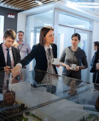 Image of several professionals discussing a miniature model of a facility under glass.