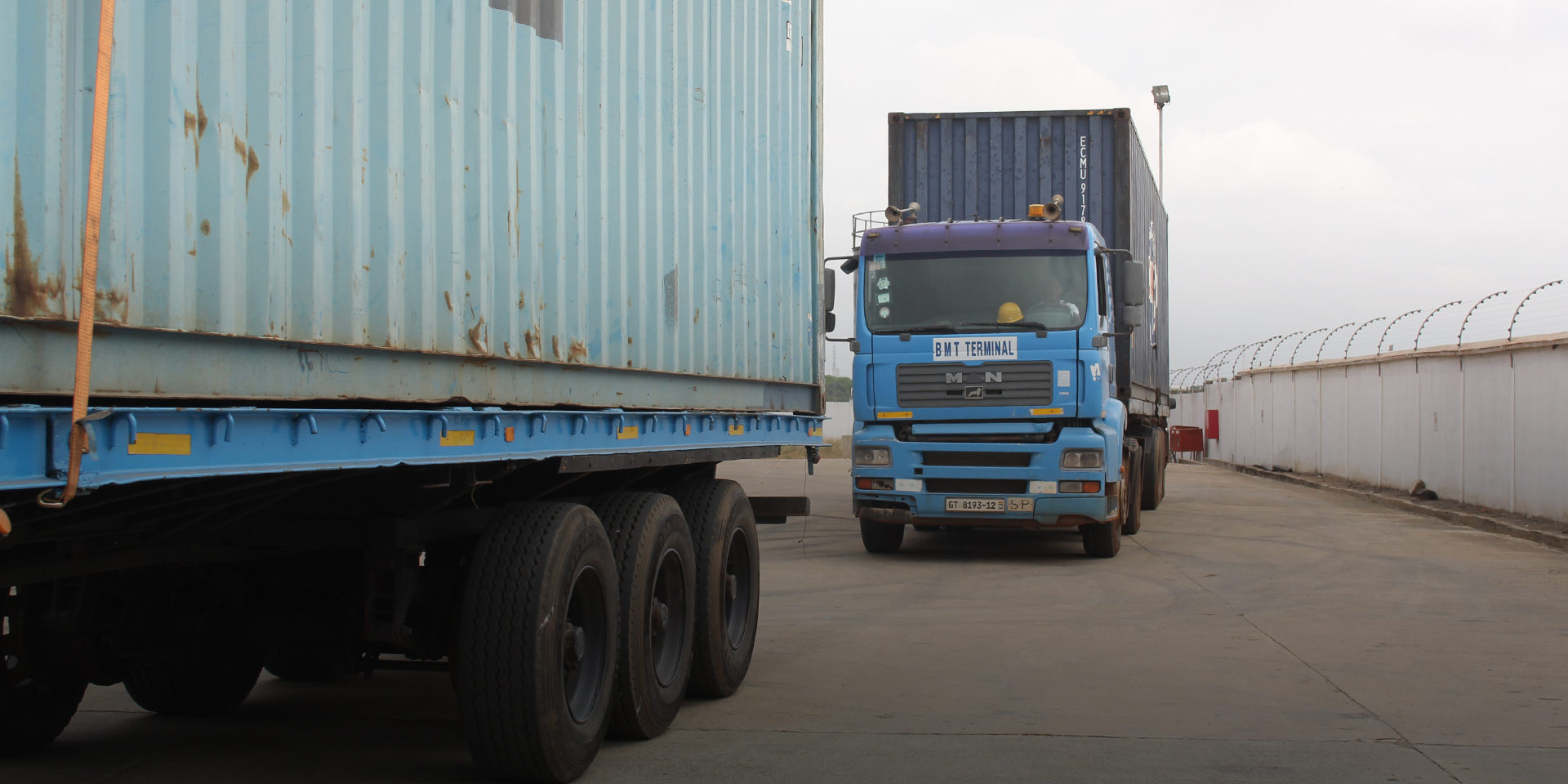 Image of two large, blue trucks driving down a road.