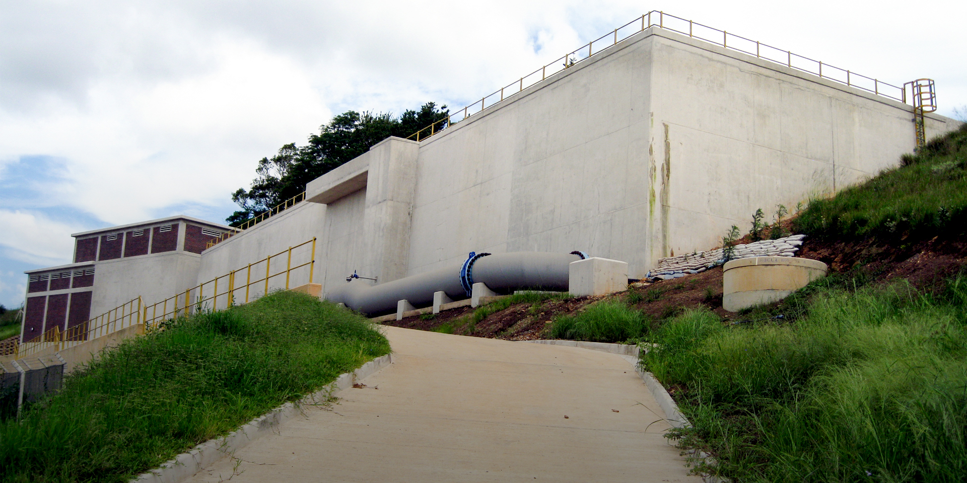 Image of a paved road going up a hill to a large water treatment building.