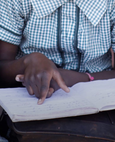 A close-up image of three children reading a notebook together.