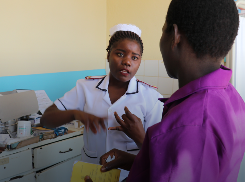 A healthcare worker speaking with a woman in a doctor's office.