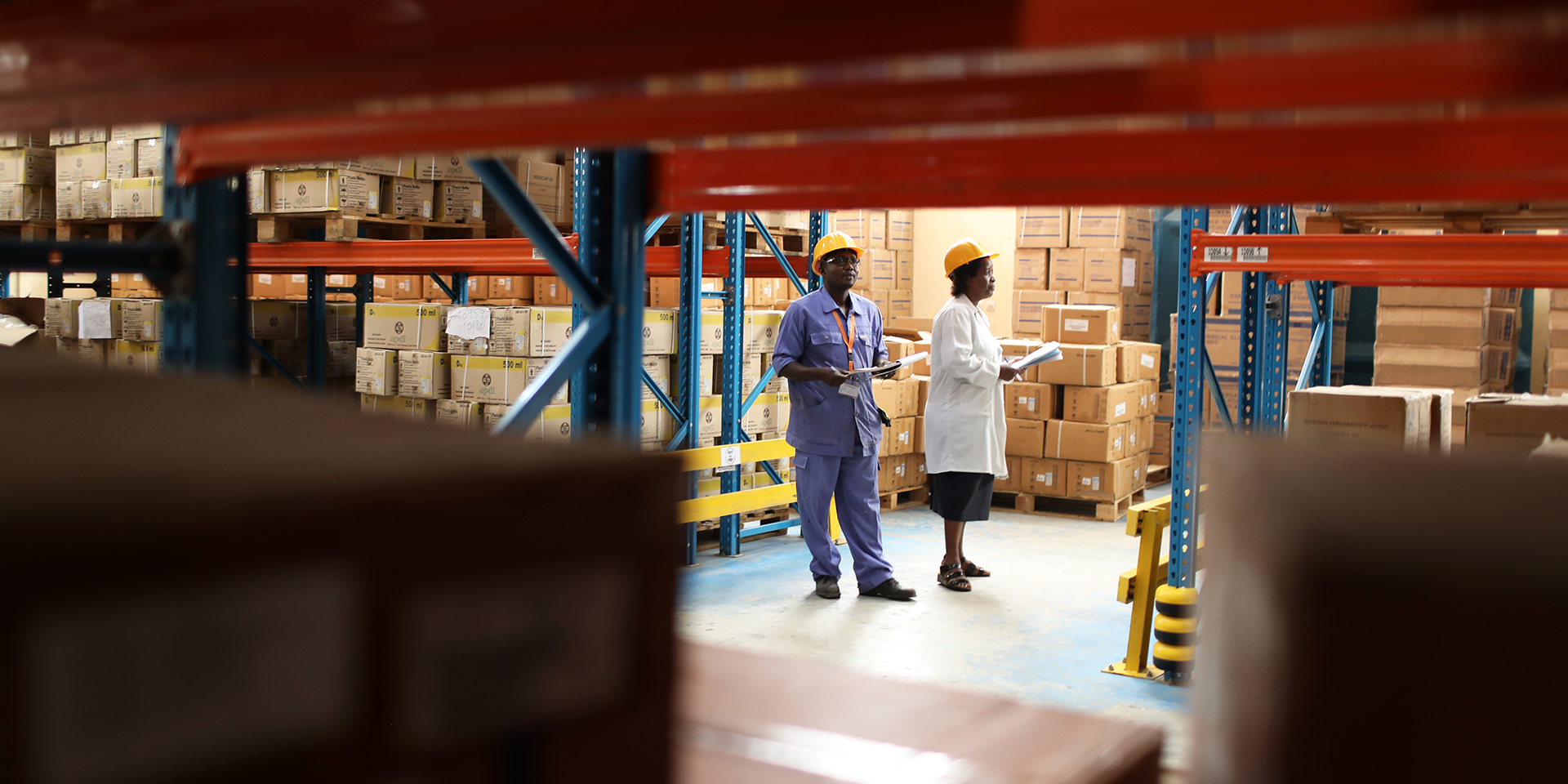 Image of two workers with hard hats standing in a warehouse filled with boxes.