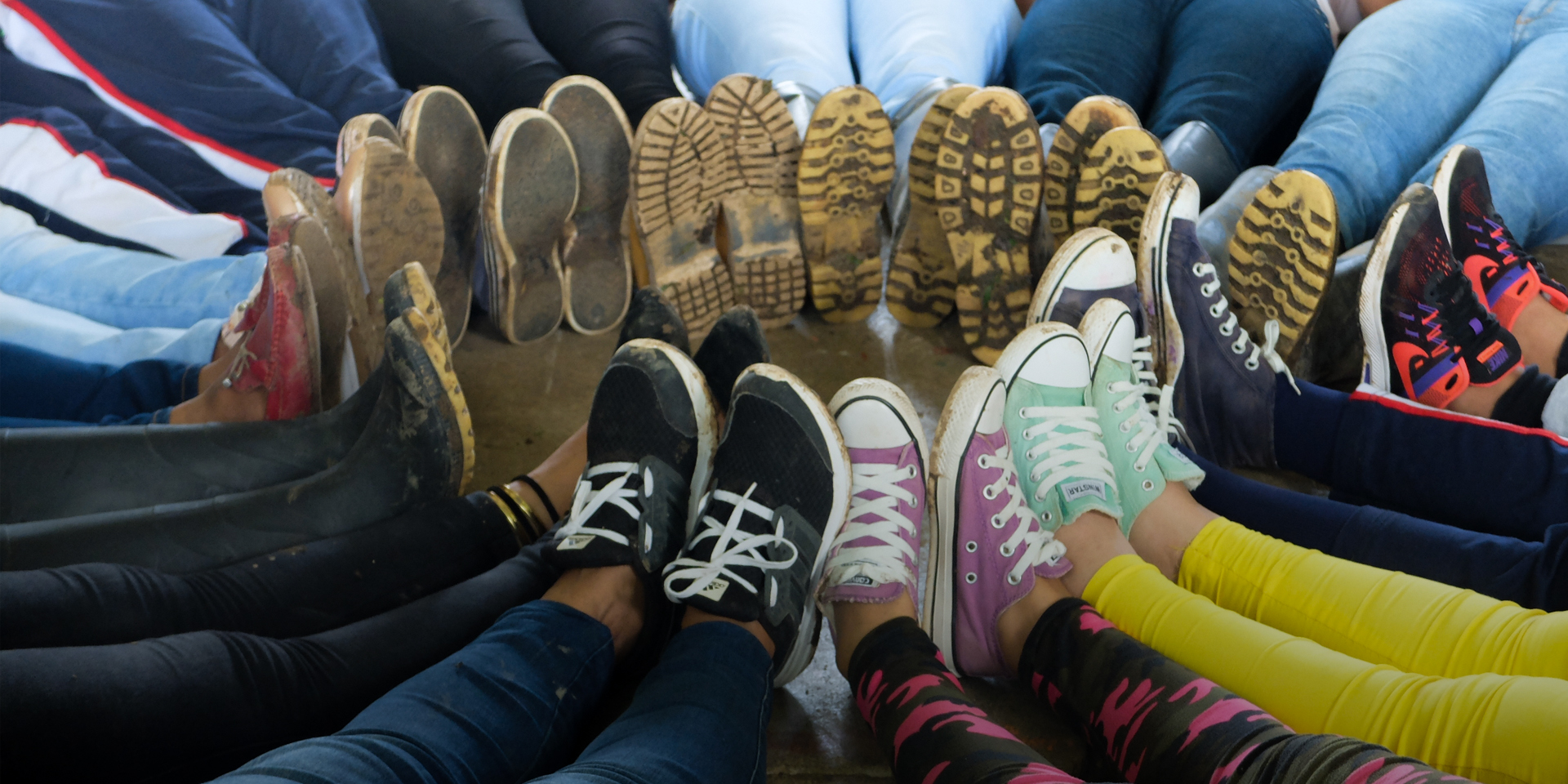 Image of several people putting their shoed feet together in the shape of a circle.
