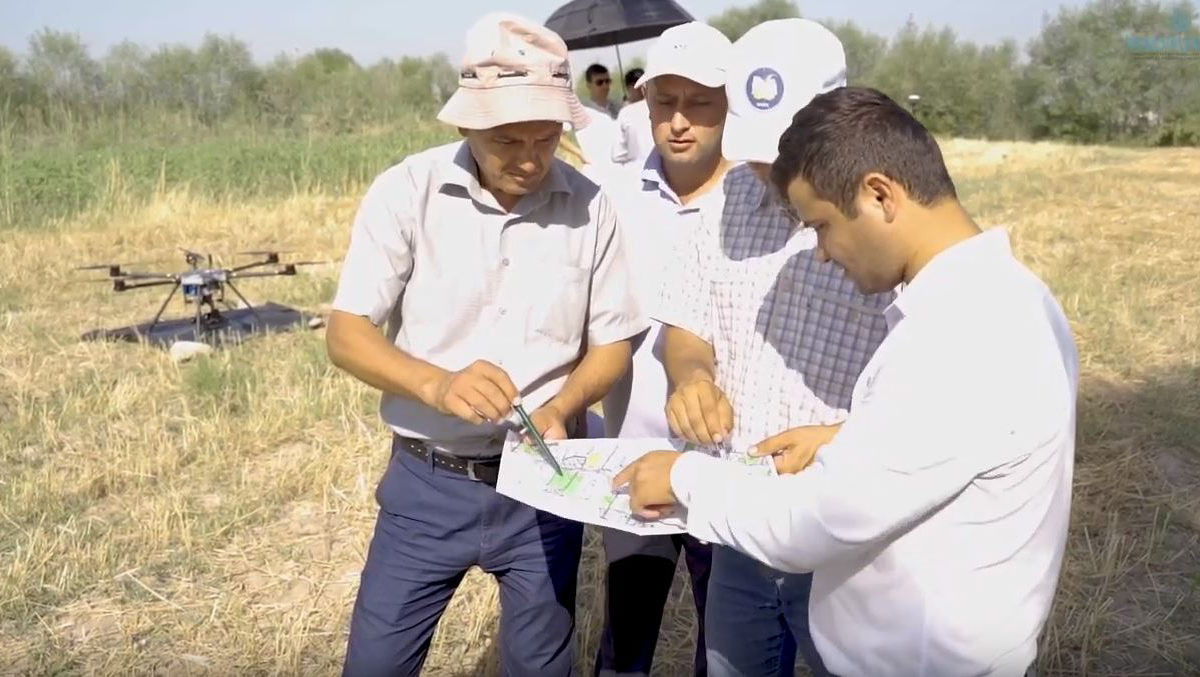 Group of men study a land survey map with drone in the background