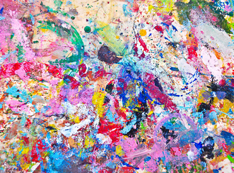 Image of several colorful paints splattered on a canvas.