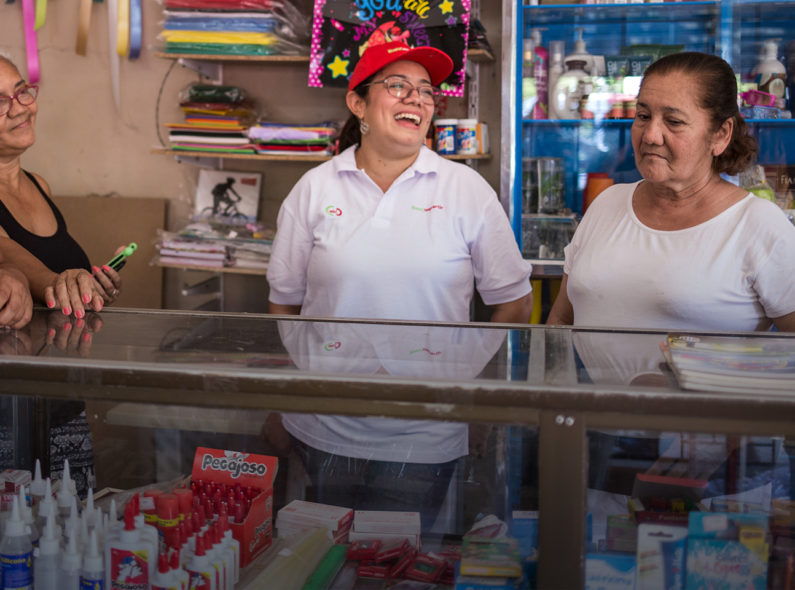 Four women socialize around a store counter in Colombia