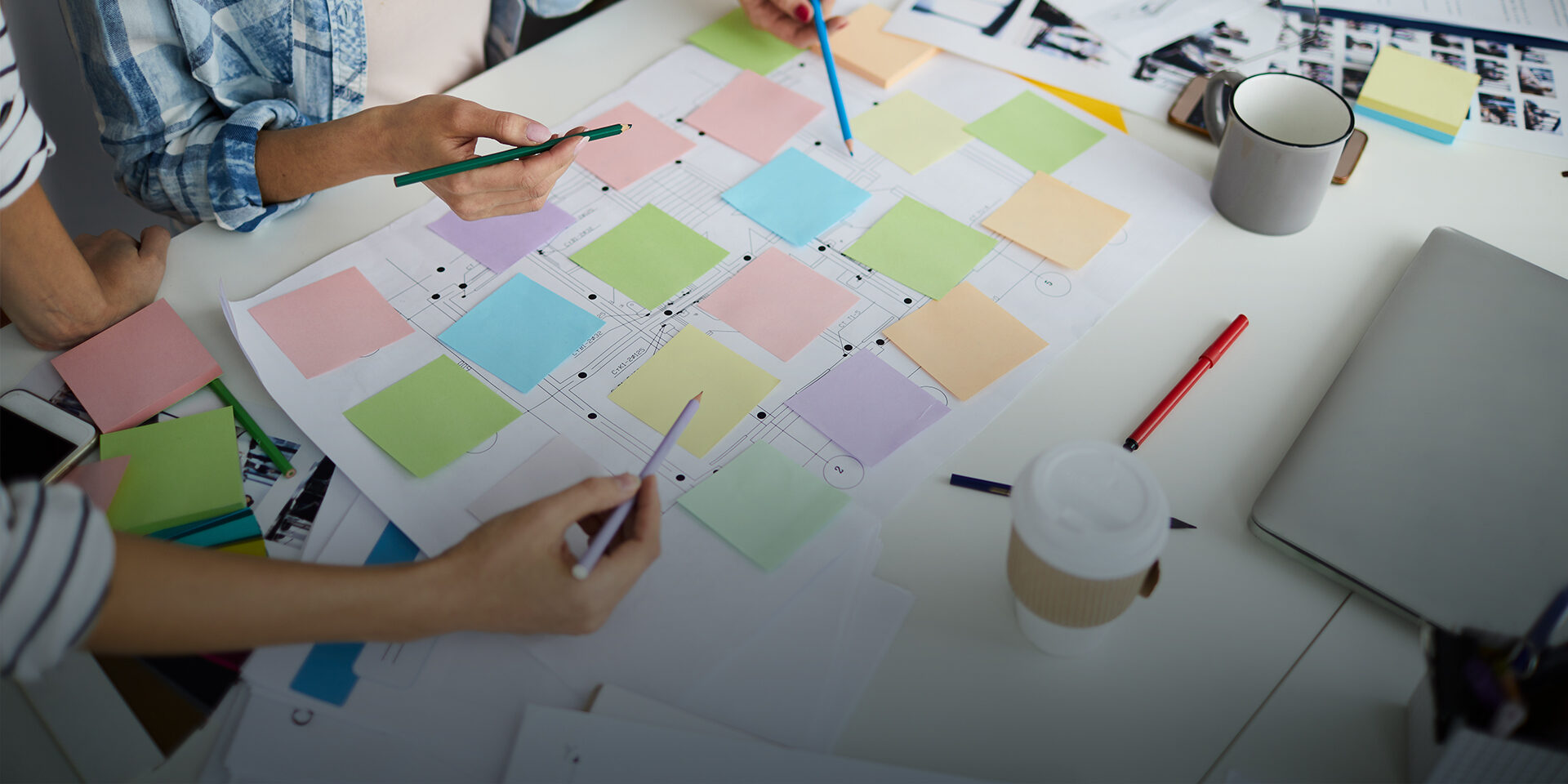 Image of two people working on a document covered with sticky notes on a table.