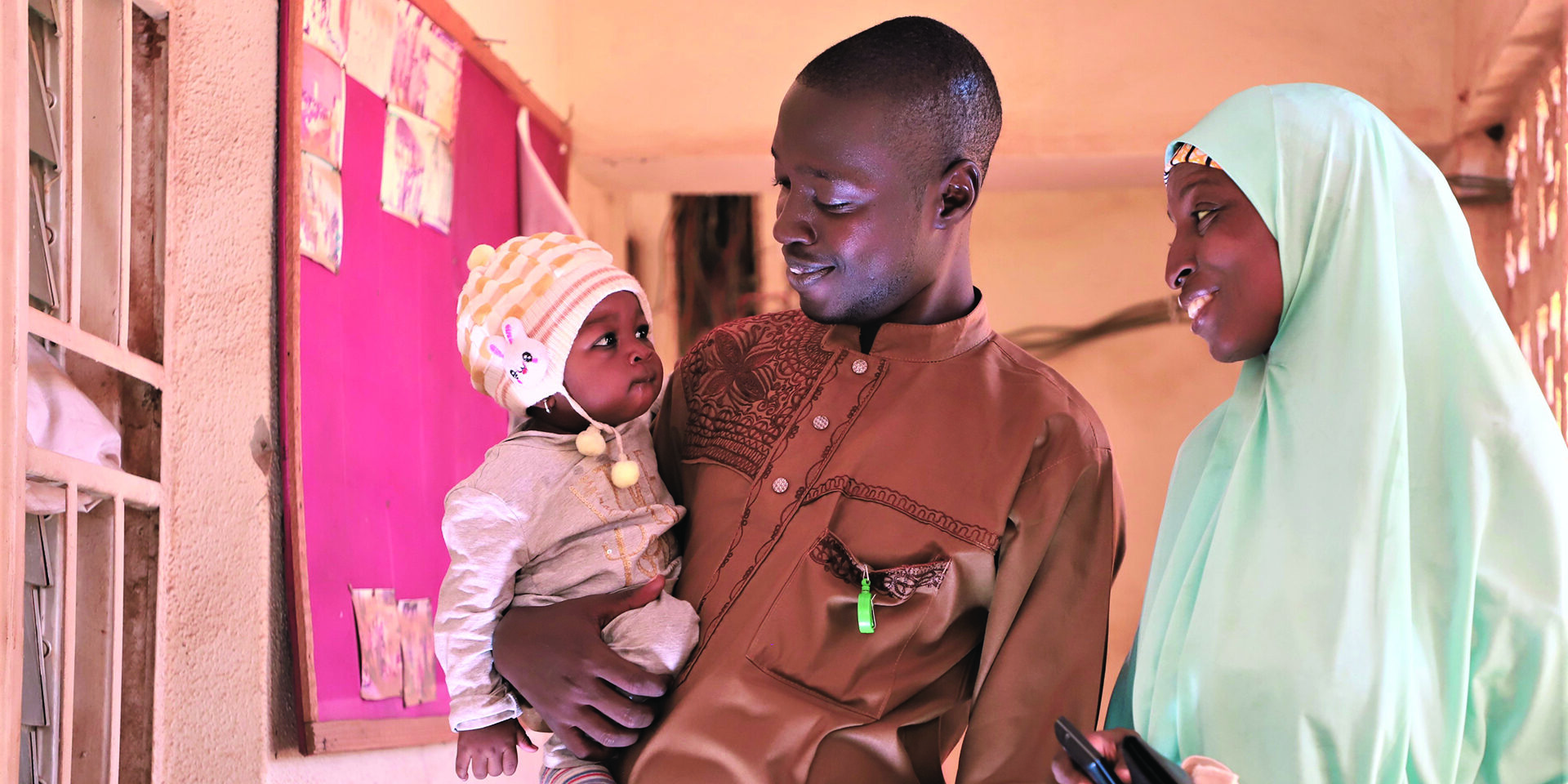 Image of a couple with a baby standing in a home and smiling.
