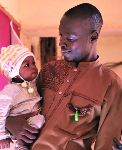 Image of a couple with a baby standing in a home and smiling.