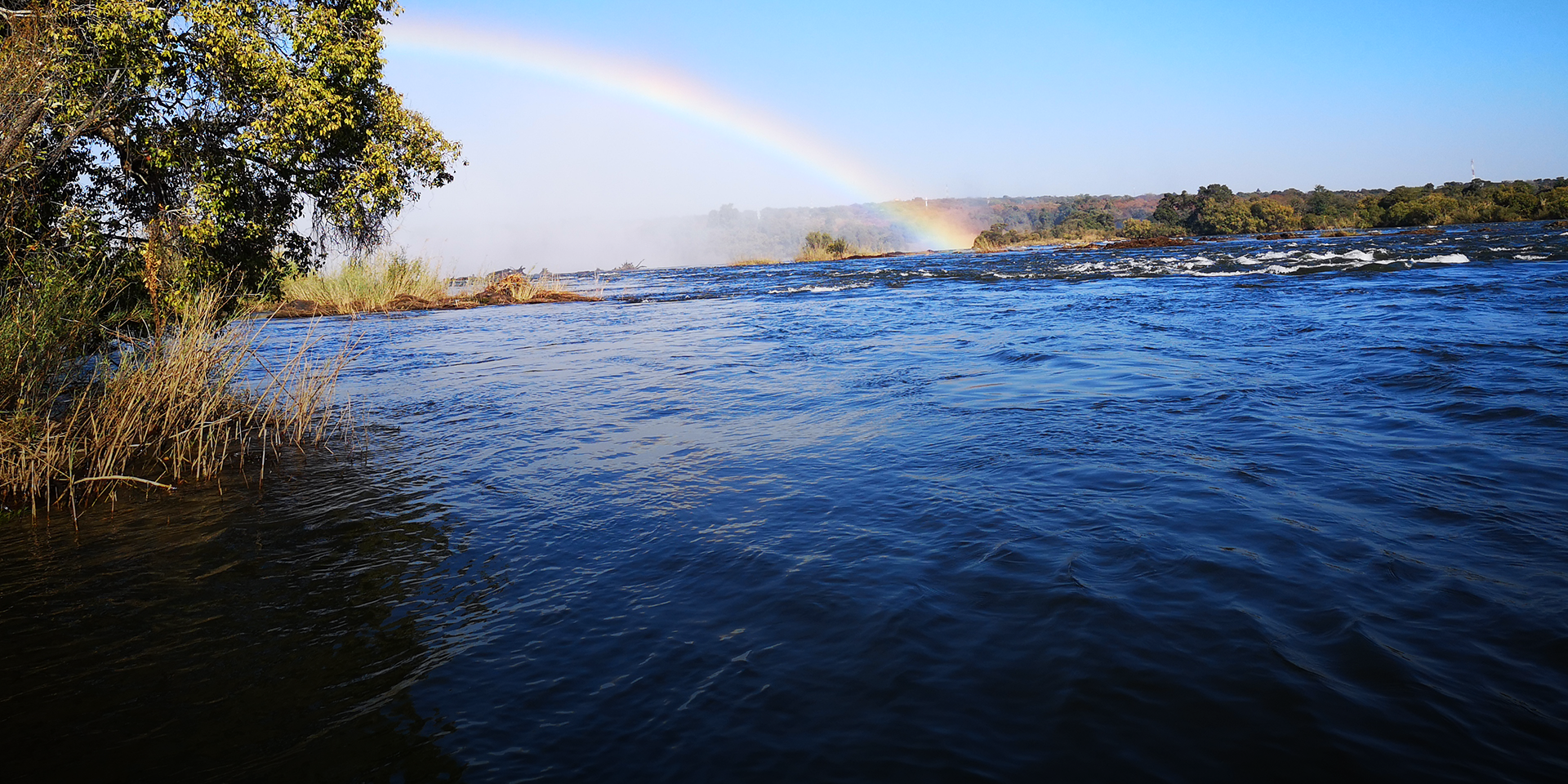 Image of a flowing river with a rainbow in the sky.