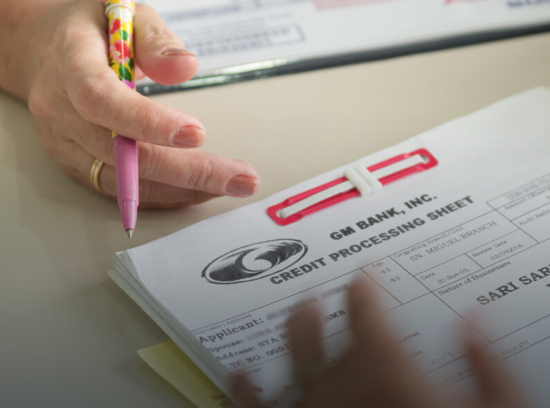 A close-up image of a credit processing form with a hand holding a pen above it.