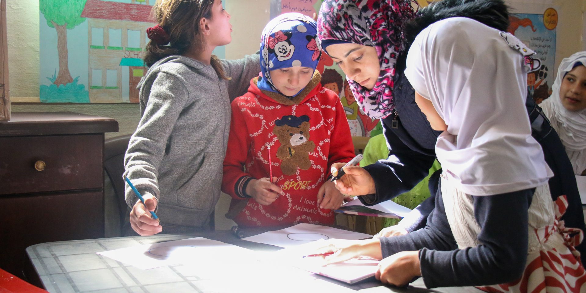 A teacher in Syria supports her students to draw pictures.