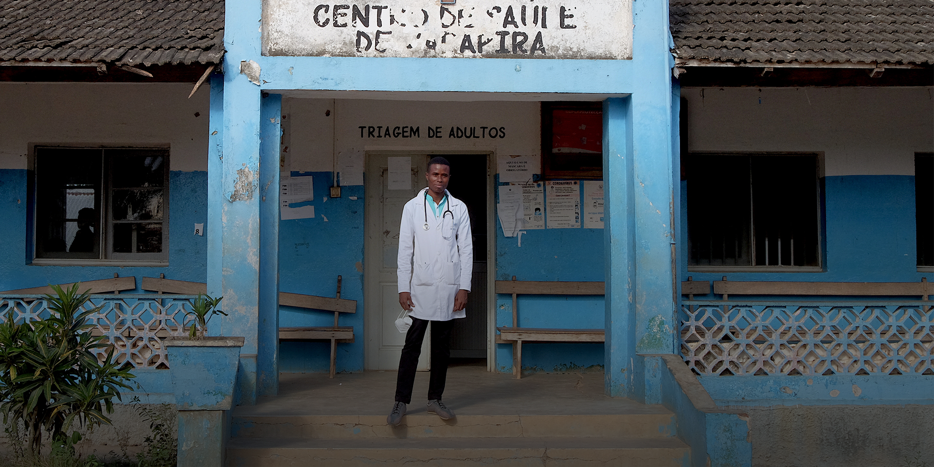 A doctor posing for a photo in front of a clinic.