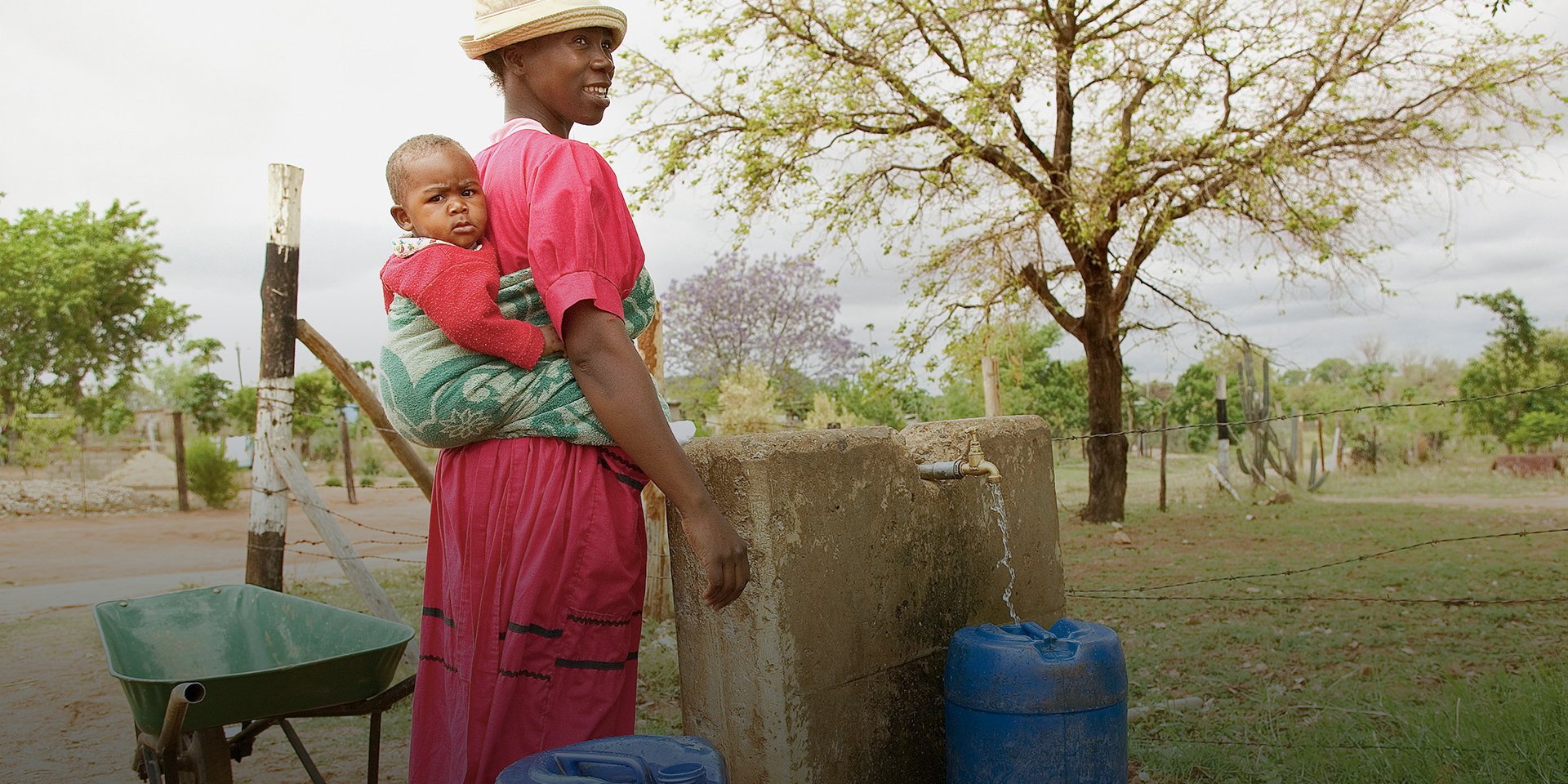 A woman and her child fill barrels with water in South Africa.