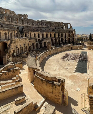 A view of an ancient Coliseum with weathered walls and a well-maintained arena.