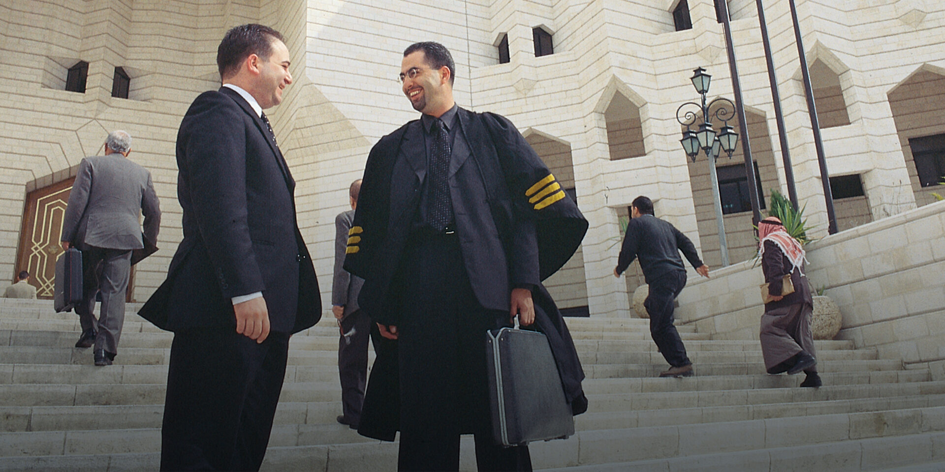 A judge speaking with a man in a suit on the steps of a large building.
