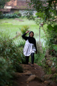 A woman waves surrounded by greenery. Photo by: Josh Estey for the USAID Indonesia Program Representasi (ProRep) photo collection.