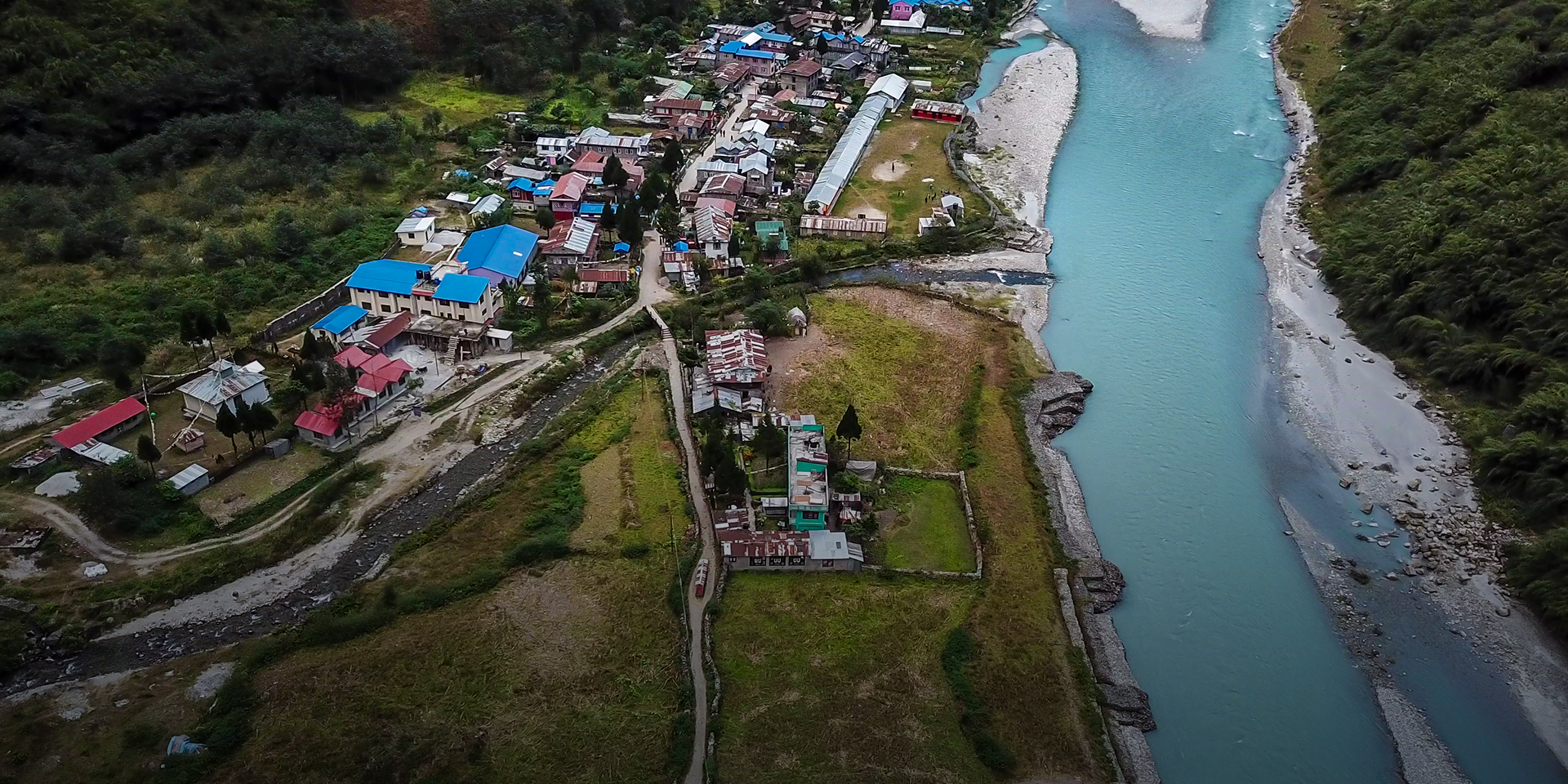 An aerial view of a large town on the edge of a blue river.