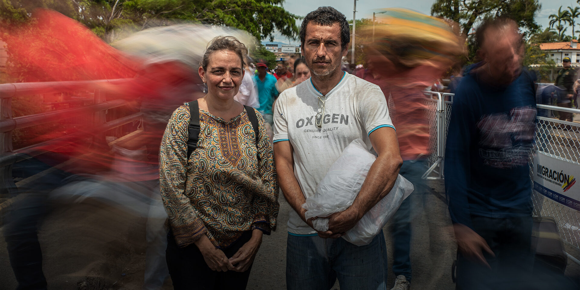 A man and a woman posing on a busy street.