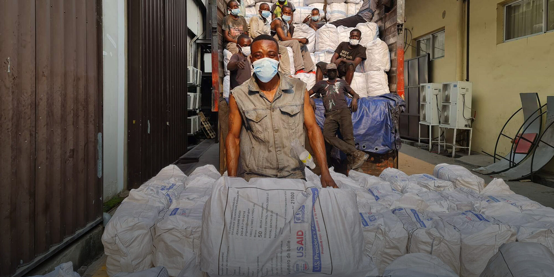 Several men posing for a photo as they load large white sacks marked 