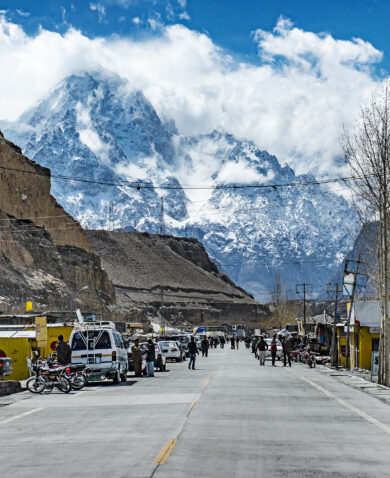 A wide road with people and cars on it, surrounded by mountains